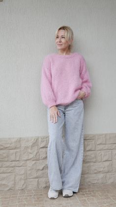 an older woman in pink sweater leaning against a wall