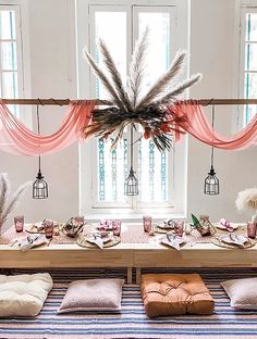 the table is set up for a party with feathers hanging from it's ceiling