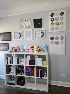 a white book shelf filled with lots of stuffed animals and pictures on the wall behind it