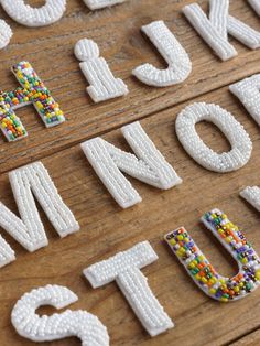 the letters and numbers are made out of beaded beads on a wooden table top