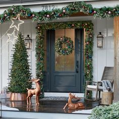 the front porch is decorated for christmas with wreaths and deer figurines on it