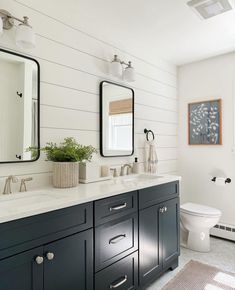 a white and black bathroom with two mirrors on the wall above the sink, toilet and bathtub