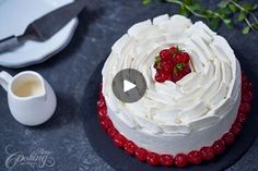 a cake with white frosting and strawberries on top next to a cup of coffee