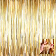 a hand is reaching up to the wall with gold tinsele curtain behind it