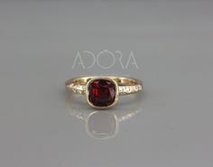 a gold ring with a red stone in the center