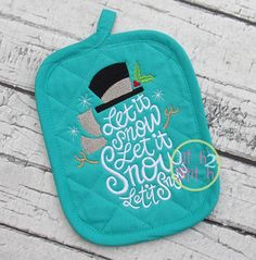 a teal pot holder with the words let's snow and a hat on it