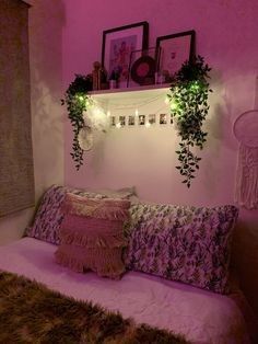 a bed with pillows and plants on the headboard in a room that has pink walls