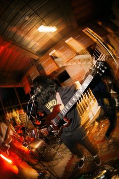 a man with long hair playing guitar on stage