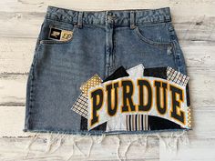 *READY TO SHIP* This ladies size 14 Purdue University Boilermakers themed denim patch skirt the perfect way to show support to your favorite school! I began with a size 14 gently worn Wild Fable brand denim skirt and have sewn Purdue University fabrics on the front & back of the skirt along with a rescued t-shirt piece to create a unique one of a kind design.   The following details & measurements will help you decide if the fit would be right for you. *Fabric content: 99% cotton/1% spandex *Waist laying flat: 16.75" *Around the "outside" of the waistband, through the belt loops: 34.25" *Hip laying flat: 21" *Length (measured from the side): 16.25" The edges of the fabric pieces will intentionally fray. This gives them the desireable "vintage" fray appearance. The more the skirt is washed College Skirt, Patch Skirt, Bed Party, Rush Week, Boilermaker, Football Wags, Patch Denim, Patchwork Clothes, Purdue University