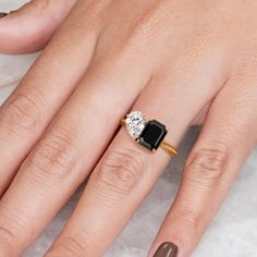 a woman's hand with a diamond and black onyxite ring in gold