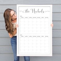 a woman holding up a large white calendar