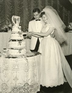 a bride and groom are cutting their wedding cake at the table in front of them