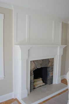 an empty living room with a fireplace in the center and white painted walls on either side