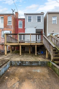 a back yard with stairs leading up to the second floor and two story houses in the background