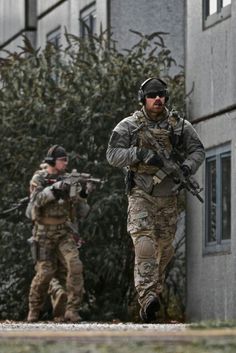 two men in camouflage gear are walking down the street