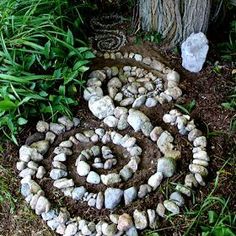 a rock garden is shown in the grass next to a tree and some rocks on the ground