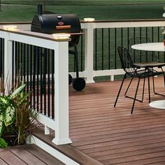 a deck with table and chairs next to a bbq grill on top of it