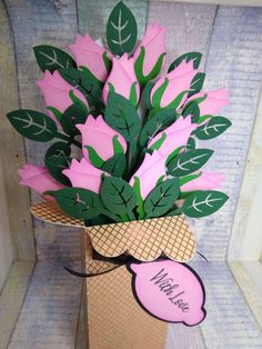 pink flowers are in a cardboard box with green leaves