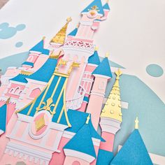 a close up of a paper cut out of a castle with gold and pink decorations