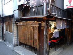 a person sitting at a table in front of a building with lots of strings hanging from it