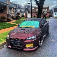 a purple car parked on the side of a road next to houses and trees in front of them