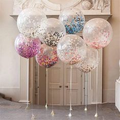 large clear confetti filled balloons in front of a fireplace