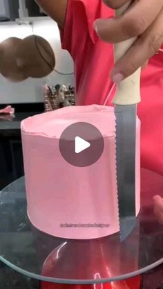 a person cutting a cake with a knife on top of a glass table in front of a counter