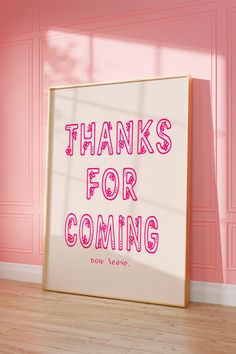 a sign that says thanks for coming in front of a pink wall and wooden floor