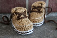 a pair of crocheted baby shoes with brown bows