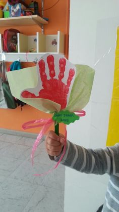 a young boy holding up a paper flower