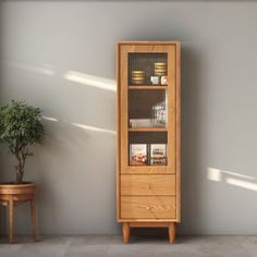 a tall wooden cabinet sitting next to a potted plant