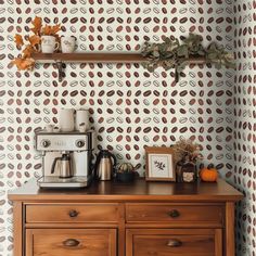 a coffee maker on top of a wooden dresser in front of a wallpapered wall