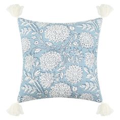 a light blue pillow with white flowers and tassels on the front, sitting on a white background