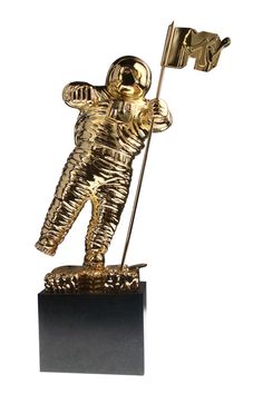 a gold statue of an astronaut holding a flag