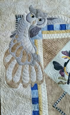 a close up of a quilted bird on a table top with blue and white stripes