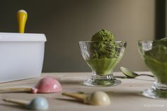 two bowls filled with green ice cream on top of a table next to eggs and spoons