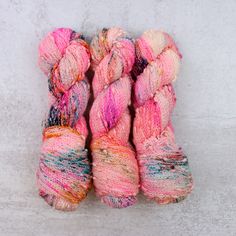 three skeins of yarn sitting next to each other on top of a white surface