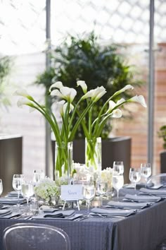 the table is set with white flowers and wine glasses