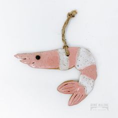 a pink and white ceramic fish ornament hanging from a rope