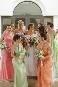 a group of women standing next to each other in front of a building holding bouquets