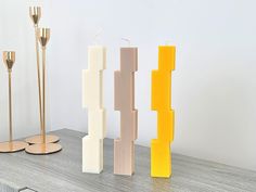 three candles sitting on top of a table next to two vases and one candle holder