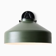 a green light hanging from the side of a white wall with a black metal fixture