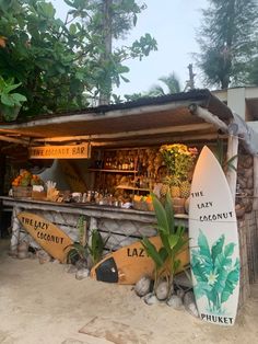 a surfboard sitting in front of a bar on the beach with plants growing out of it