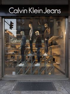 three mannequins are in the window of a clothing store