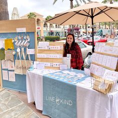 a woman standing in front of a table with cards on it and an umbrella over it