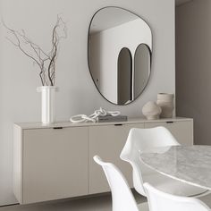 a white table with chairs and a round mirror on the wall