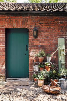 a brick building with potted plants next to a green door