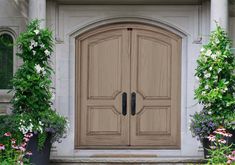 a large wooden door in front of some flowers