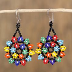 colorful beaded earrings hanging from a wooden stick on top of a piece of wood