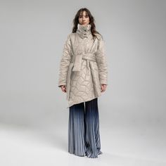 a woman wearing a coat and pleated pants